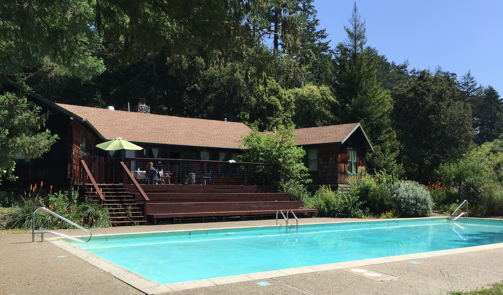 photo of the Pescadero retreat center with the pool in the foreground and forest in the background